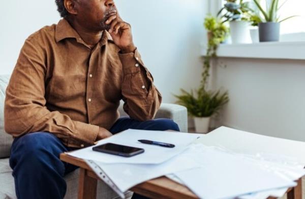 Depressed Senior Adult Man With Stacks of Papers and Envelopes
